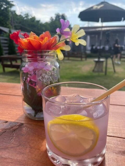 a glass of lemonade and a jar of flowers on a table