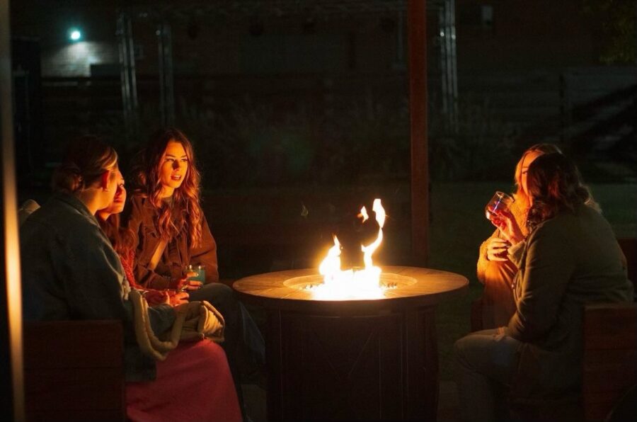 three people sitting around a fire pit at night